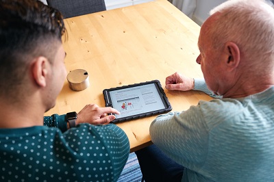 Zorgverlener en client kijken samen naar een tablet
